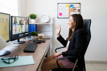 Marketer sitting in a chair waving at a screen of people